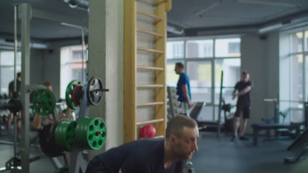 Spor salonunda kettlebell ile egzersiz yapan kaslı bir adam. — Stok video