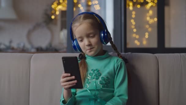 Gadis di headphone mendengarkan musik di ponsel — Stok Video
