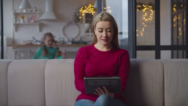 Sevgi dolu bir kız, evde tablet bilgisayar kullanarak annesini kucaklıyor. — Stok video