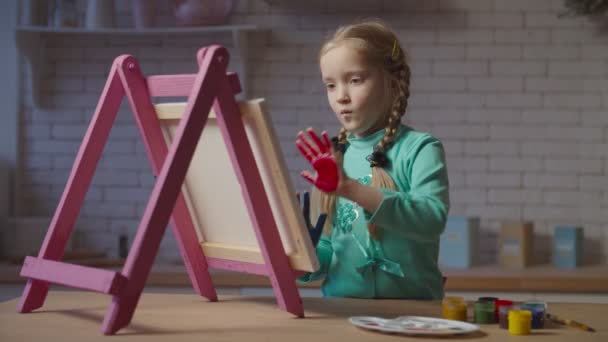 Klein meisje schilderen met de handen geschilderd op ezel — Stockvideo