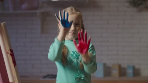 Schattig klein meisje met handen in kleurrijke verven — Stockvideo