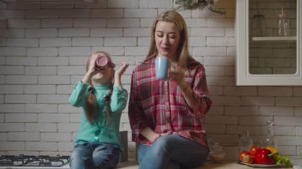 Сім'я з гарячими напоями сидить на кухонній стільниці — стокове відео