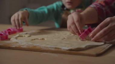 Eller hamurdan kurabiye kesiciyle form kesiyor.