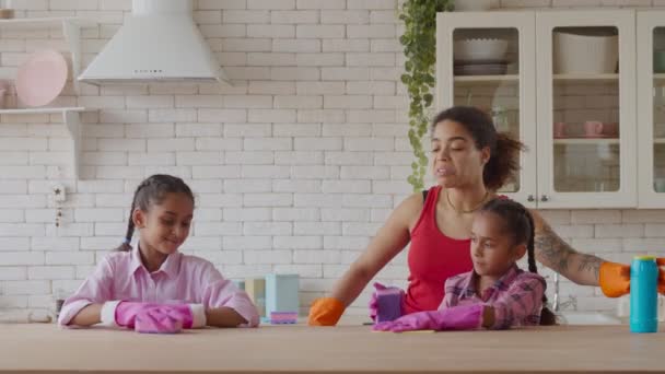 Afrikaanse moeder en meisjes schoonmaken tafel met wasmiddel — Stockvideo