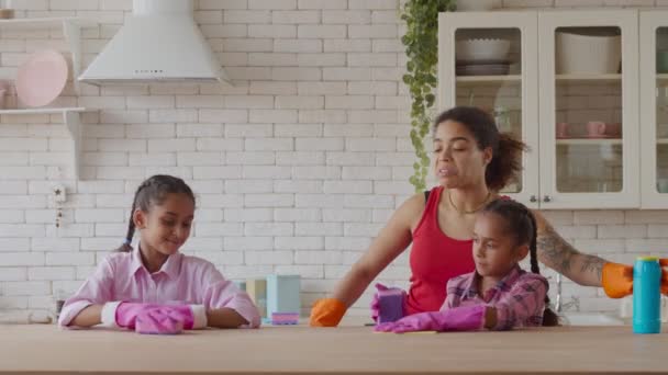 Afrykańska mama i dziewczyny sprzątanie stół z detergent — Wideo stockowe