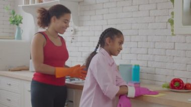 Pozitif anne ve küçük çocuk tezgahı temizliyor.