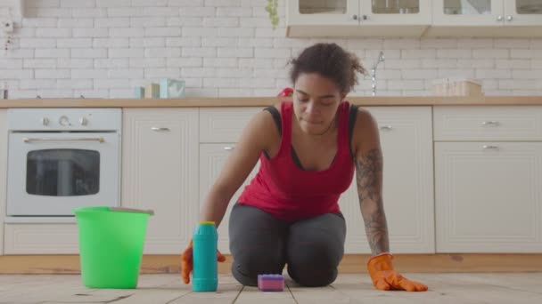 Kneeling african woman wiping floor with detergent — Stock Video