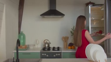 Esnek, güzel bir kadın buzdolabını kapatmak için bacağını esnetiyor.