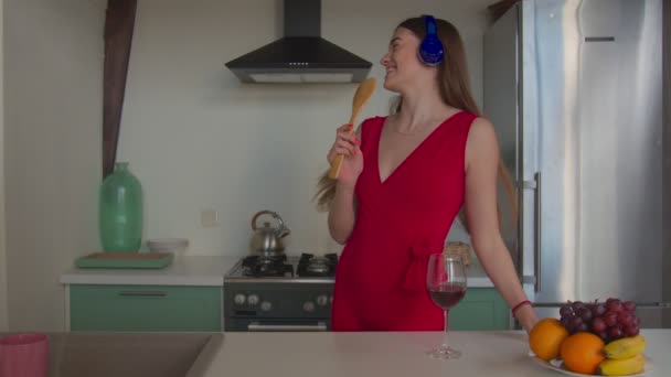 Joyful woman singing into spatula in kitchen — Stock Video