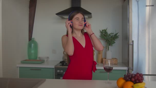 Chica despreocupada en los auriculares disfrutando de la música en la cocina — Vídeos de Stock