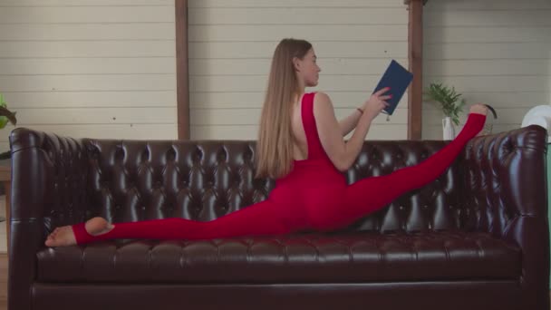 Menina desportiva com livro fazendo divisões dianteiras trechos — Vídeo de Stock