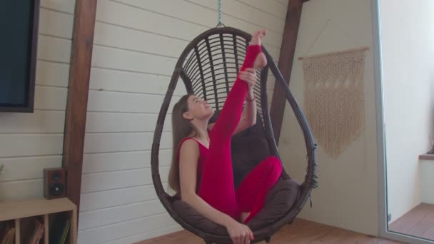 Sporty woman sitting in heron pose in swing chair — Stock Video