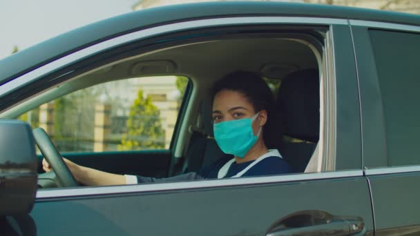 Черная женщина водитель в автомобиле в медицинской маске — стоковое видео