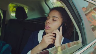 İş kadını arka koltukta cep telefonuyla konuşuyor.