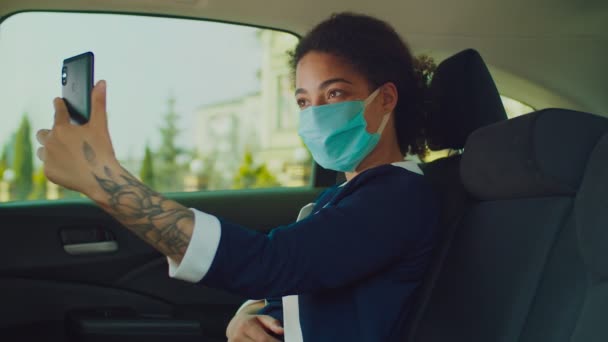 Belle femme en masque médical prenant selfie en voiture — Video