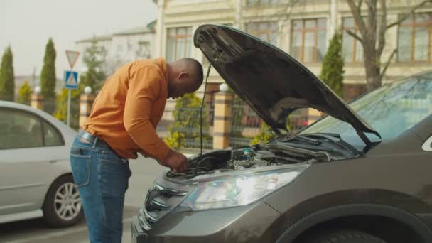 Rozrušený muž kontroluje rozbité auto motor na ulici — Stock video