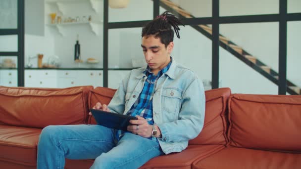 Стильный мужчина с планшетным компьютером на диване — стоковое видео