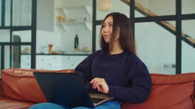 Evde dizüstü bilgisayarla çalışan Asyalı çekici bir kadın.