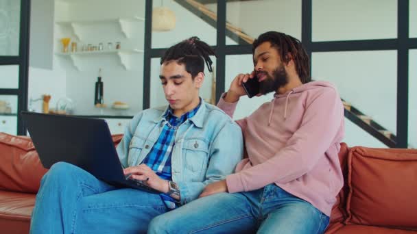 Amigos masculinos multirraciales con gadgets relajándose en el sofá — Vídeo de stock