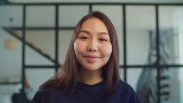 Freudig liebenswert junge asiatische Frau lächelt drinnen — Stockvideo