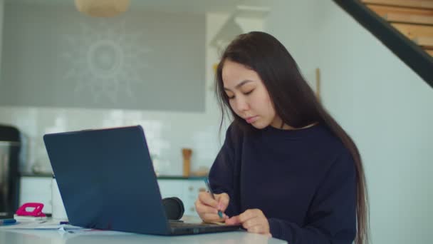 Pensive asian woman browsing online on laptop — Stock Video