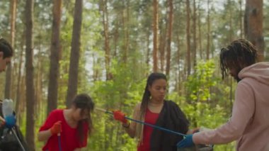 Çeşitli insanlar ormanda çöp ve plastik topluyor.