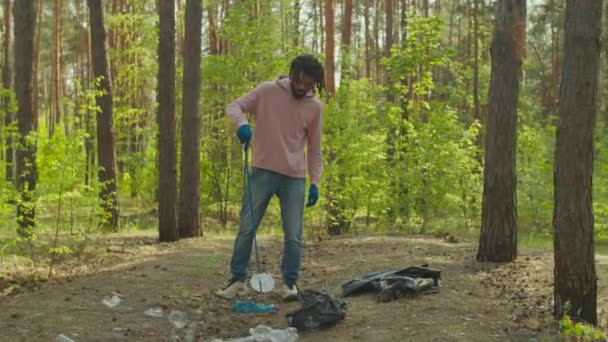 Black man volunteer with tool cleaning forest trash — Stock Video