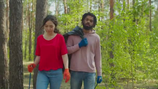 Multiraciale vrijwilliger paar ophalen van afval in het bos — Stockvideo