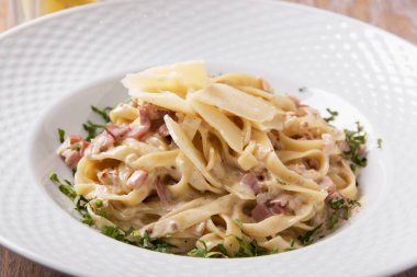 makarna carbonara parmesan ve yeşillik bir plaka üzerinde