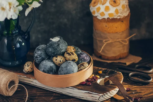 Yuvarlak ahşap kutunun içindeki paskalya yumurtaları kırsal ahşap arka planda elma çiçeği dallarıyla birlikte..