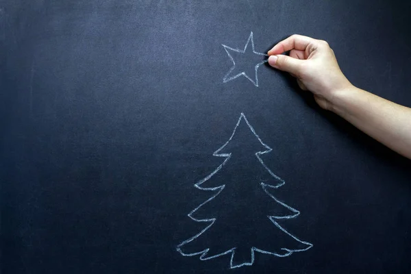 Julgran och barnets hand med stjärna på blackboard abstrakt bakgrund koncept — Stockfoto