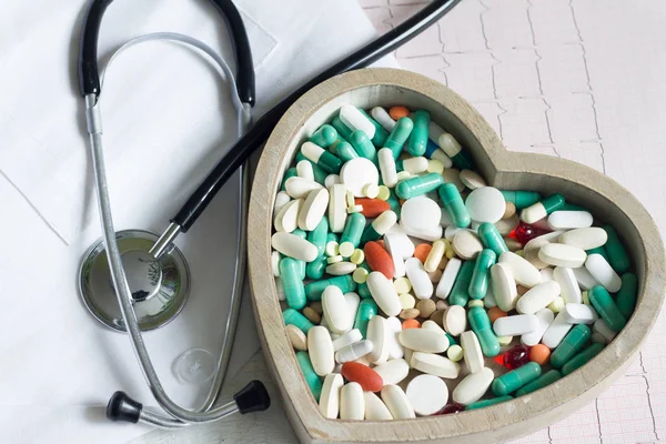 Stethoskop und Pillen im Herzen gegen kardiogrammmedizinisches Konzept — Stockfoto