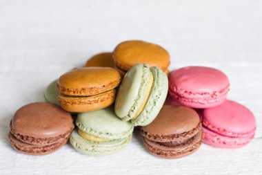 Renkli macarons, bademli kurabiye pasta Beyaz ahşap arka plan üzerinde