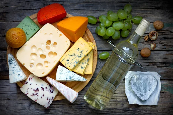 Various types of cheese with bottle of wine on old retro boards still life — Stock Photo, Image