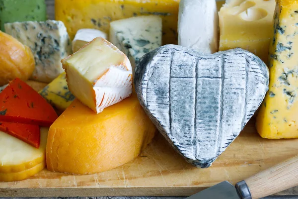 Queso en forma de corazón en tablas viejas alimentos coloridos bodegón abstracto — Foto de Stock