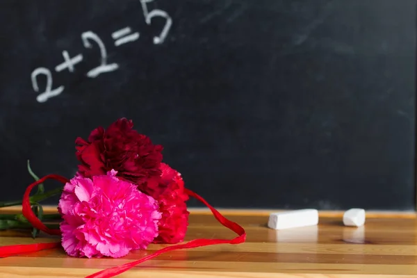 Flores y pizarra en el concepto de fondo del día del profesor de clase — Foto de Stock