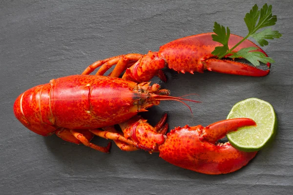 红色龙虾与香菜和石灰在爪子在黑石头乐趣海鲜概念 — 图库照片
