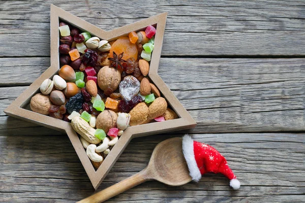 ナッツとドライフルーツは 木製ボード上のスプーンとサンタの帽子とクリスマスのためのミックス — ストック写真