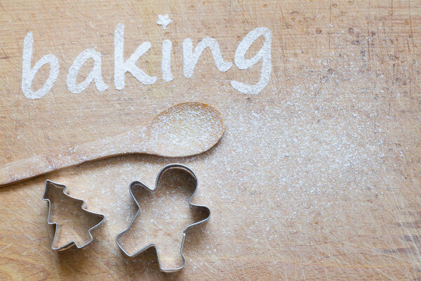 Christmas background with cookies molds and spoon. Baking text made with flour