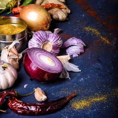close-up view of peppers, onions, garlic, ginger and curry powder on blue clipart