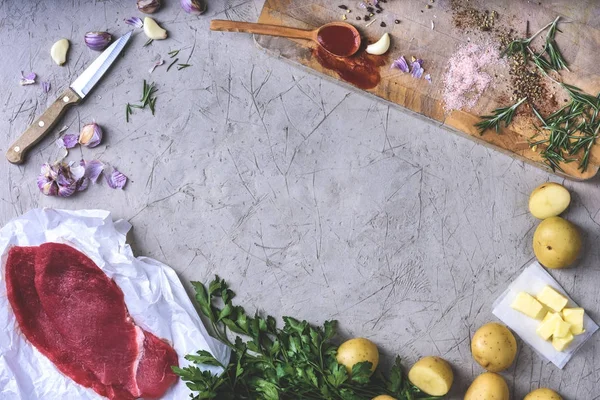 Draufsicht auf Kartoffeln mit Butter, Holzlöffel mit Tomatensauce, Gewürzen und rohem Fleisch auf grau — Stockfoto