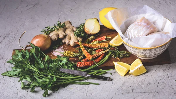 Nahaufnahme von gesundem rohem Fisch in Schüssel mit Gemüse und Gewürzen auf Holzschneidebrett — Stockfoto