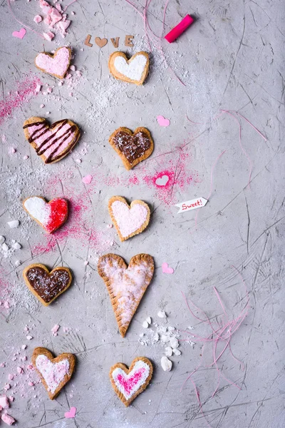 Vista superior de dulces galletas hechas a mano en forma de corazón para el día de San Valentín en la superficie agrietada gris - foto de stock