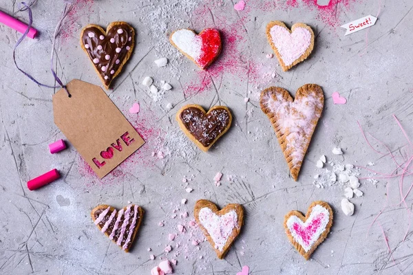 Vista superior de las galletas en forma de corazón dulce con etiqueta de amor en la superficie agrietada gris - foto de stock