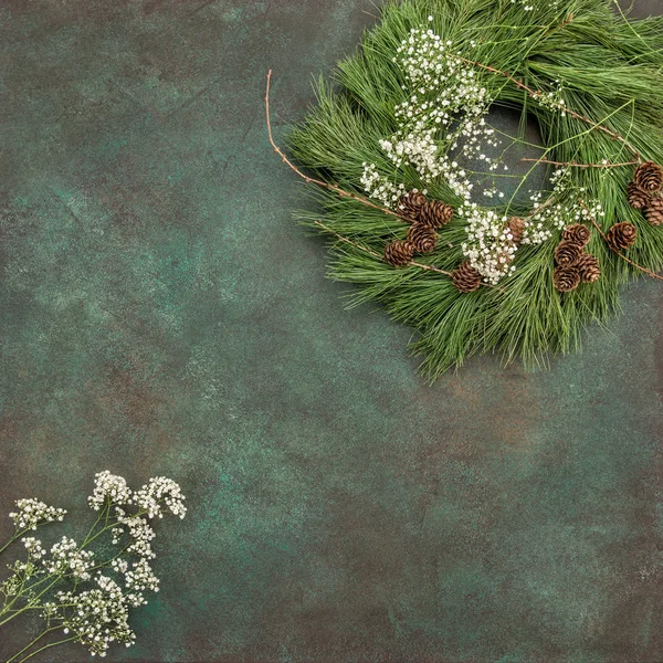 Kerst krans met dennenappels en witte bloemen — Stockfoto