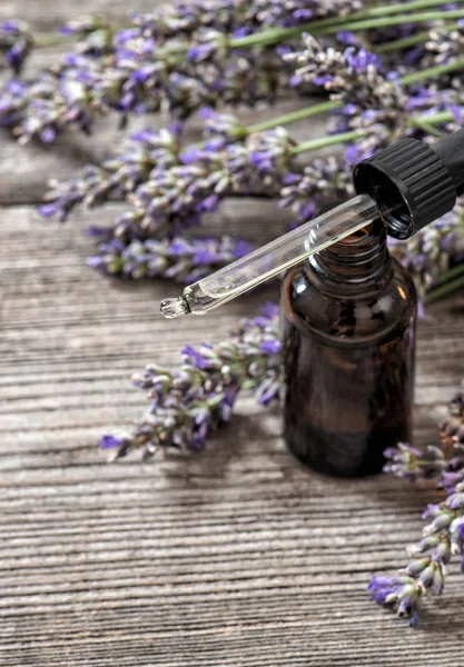 Lavendelolja essence dreied blommor trä bakgrund — Stockfoto