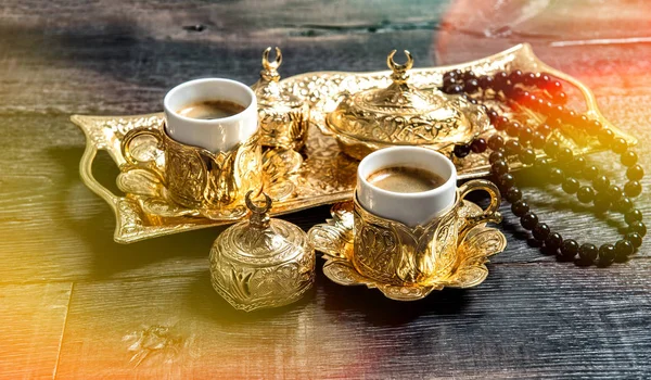 Золоті чашки кави розарій бісеру дерев'яний фон протікає світло — стокове фото