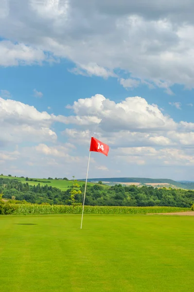 Golfové pole zelené trávě rudá vlajka zataženo modrá obloha — Stock fotografie