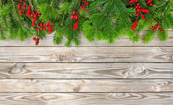 Kerstboom takken decoratie rode bessen houten achtergrond — Stockfoto
