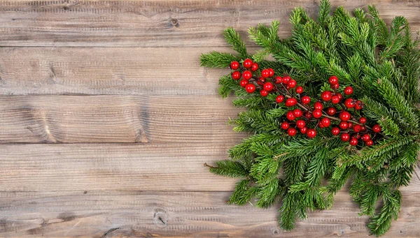 Vánoční stromek větve červené bobule dřevěné pozadí — Stock fotografie